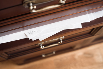 A drawer of wooden commode full of paper documents. Selective focus