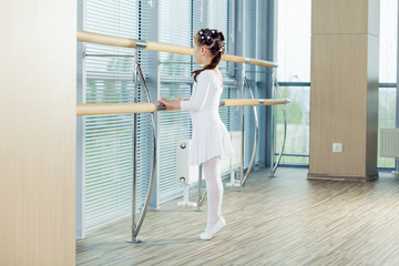 Little ballerina girl. Adorable child dancing classical ballet in a white studio.
