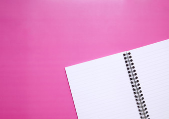 A plain lined writers journal, open on a pink background