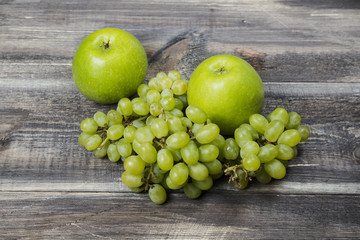 Fresh green apples and grape on wood