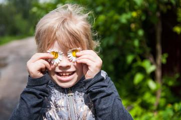 Child playing with flowers camomiles