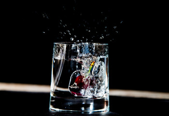 A piece of fuit falling into a glass filled with fizy drink