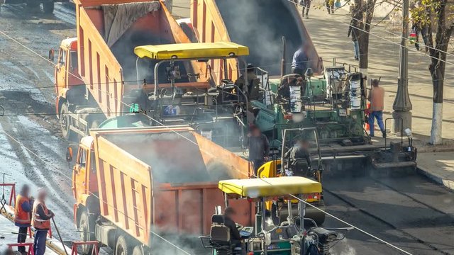 Workers operating asphalt paver machines during road construction and repairing works timelapse