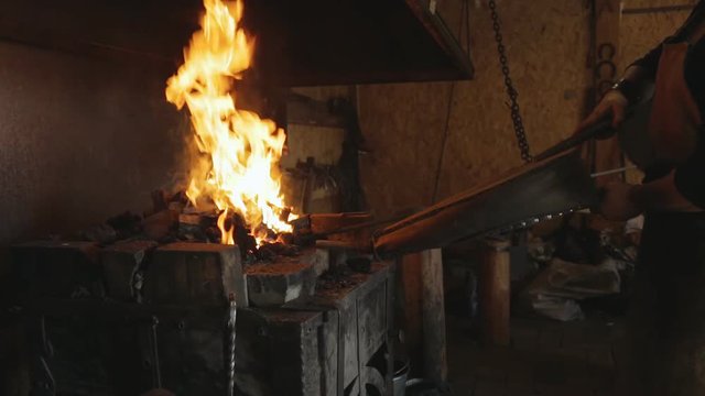 Blacksmith lit horn foment fire with leather bellows.