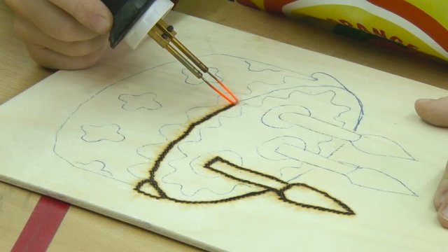 Boy's Hand Burns Picture "cake" in Technique Pyrography. Labor Lesson. Closeup. Children, Scool, Education