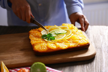 Woman cutting delicious citrus cake