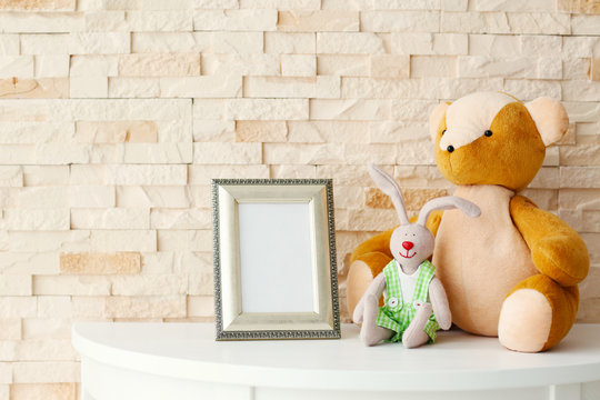 Baby toy and frame on brick wall background