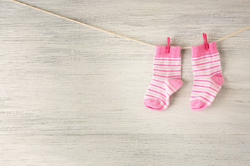 Baby socks hanging on the clothesline on wooden background