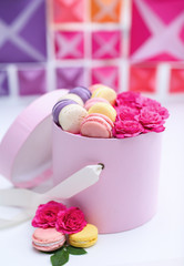 Tasty macaroons in box on colourful blurred background