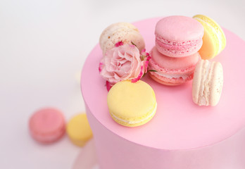 Tasty macaroons and rose in box on light background