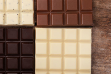 Different chocolate bars on wooden background
