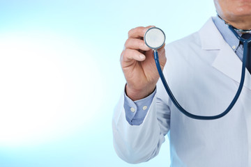 Professional doctor with stethoscope on blue background