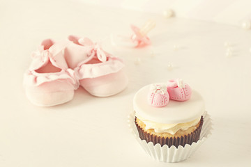 Bootees with cupcake on light background
