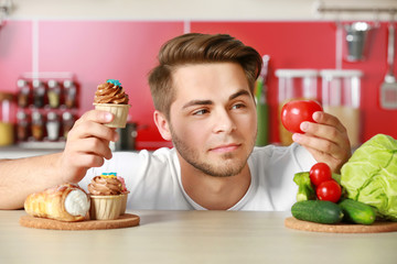 Man with healthy and unhealthy food in kitchen