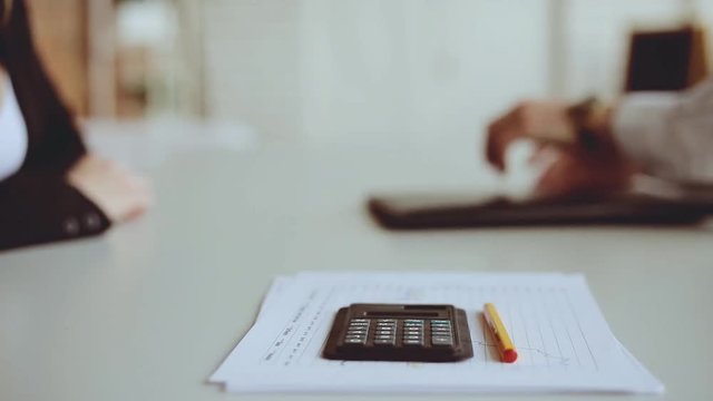 Close-up of two businessmen shaking hands while sitting at the desk and sign the contract. Business handshake