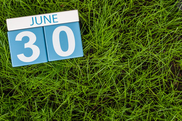 June 30th. Image of june 30 wooden color calendar on greengrass lawn background. Summer day, empty...