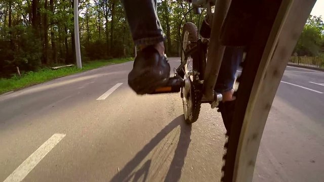 Slow motion man cyclist riding on a paved road near the forest at sunset, backlight, front camera shoots