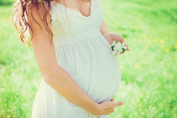 Close-up pregnant woman belly in the apple orchard