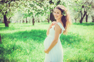 Pregnant beautiful woman in the apple orchard