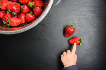 black desk background with copyspace, the child picks strawberries - Powered by Adobe