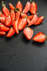 strawberries cut into pieces on black background with copyspace
