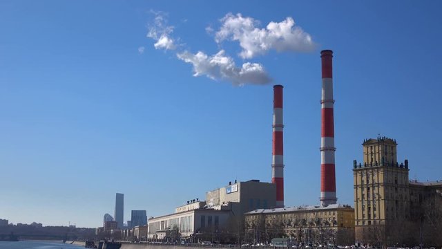 Heat electric plant and smoke from smoke stacks against blue sunny sky. 4K shot