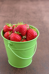 Strawberries with stems in a green bucket
