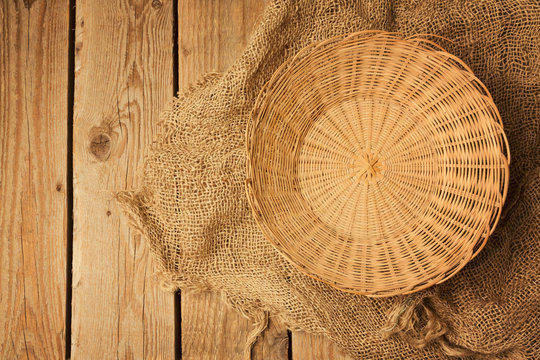 Empty Vintage Basket On Sackcloth Over Wooden Board. View From Above