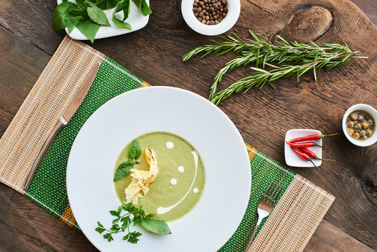 Healthy Breakfast soup with zucchini in a white plate on a wooden table