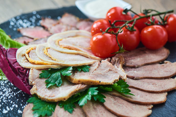 Cold cuts of roast beef, baked ham, chicken roll and beef tongue served on a stone Board