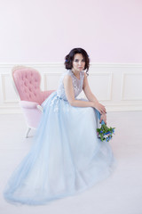 Young beautiful bride sitting in a pink chair. The Studio is all pink.