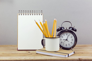 Pencils, alarm clock and notebook on wooden table. Business planinig process concept