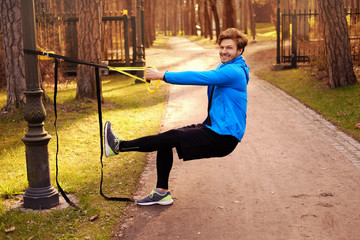 Sporty male exercising with fitness trx.