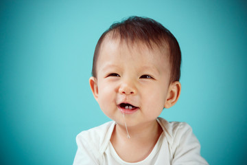Cute asian baby laughing on blue background, studio shot (soft f