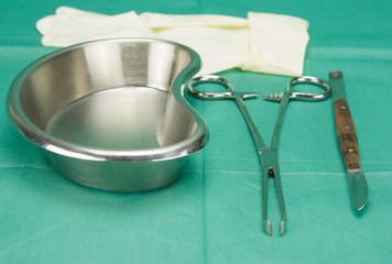 Surgical clamp and knife placed near kidney shape bowl