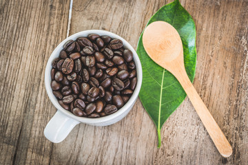 Coffee beans in cup on wooden