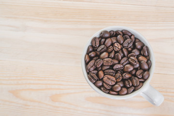 Coffee beans in cup on wooden