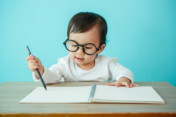 Portrait of an adorable baby girl wearing glasses on the table (