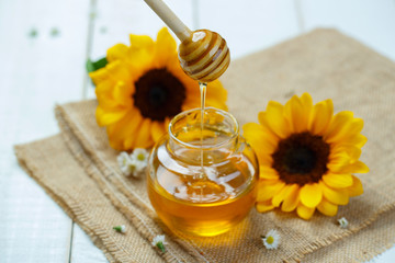 Honey jar with dipper and flowing honey, canvas background