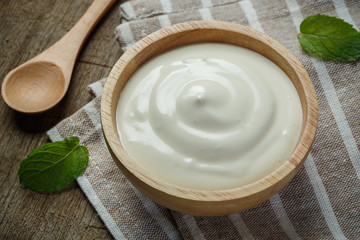 Greek yogurt in a wooden bowl with spoons on wooden background