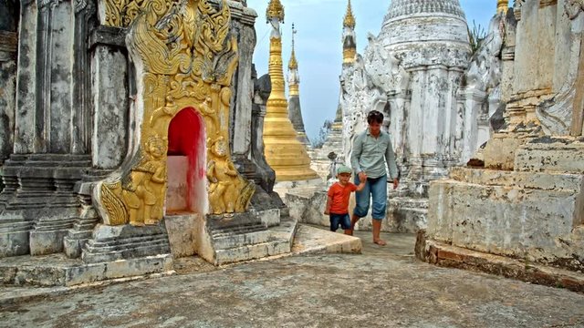 young woman walks with toddler son among the stupas in the Thaung Tho temple on Inle Lake in Myanmar (formerly Burma)