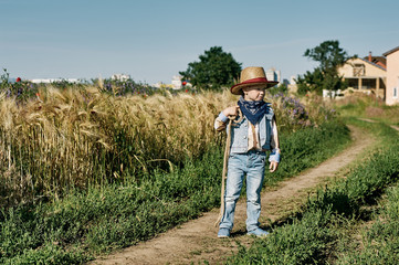 Fototapeta premium Little boy dressed in Western style in the field , retro style