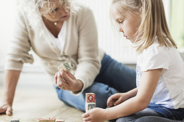 Woman and girl playing with wooden blocks 