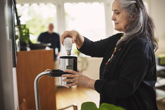 Senior woman replacing lightbulb at home 