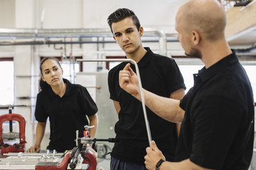 Technician teaching workers how to do metal work