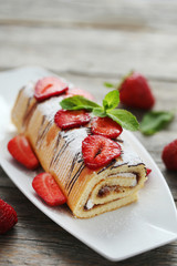 Strawberry cake on plate on grey wooden table