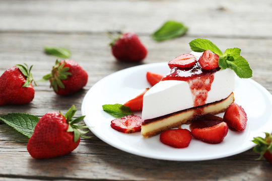 Strawberry cheesecake on plate on grey wooden table