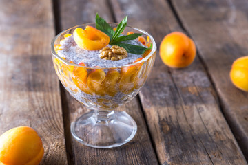 Raw vegan dessert: Chia seeds pudding with apricots and mint on a wooden background. 