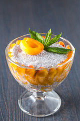 Raw vegan dessert: Chia seeds pudding with apricots and mint on a dark wooden background, close-up. 