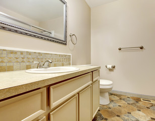 Bathroom interior with tile floor and framed mirror in small hou